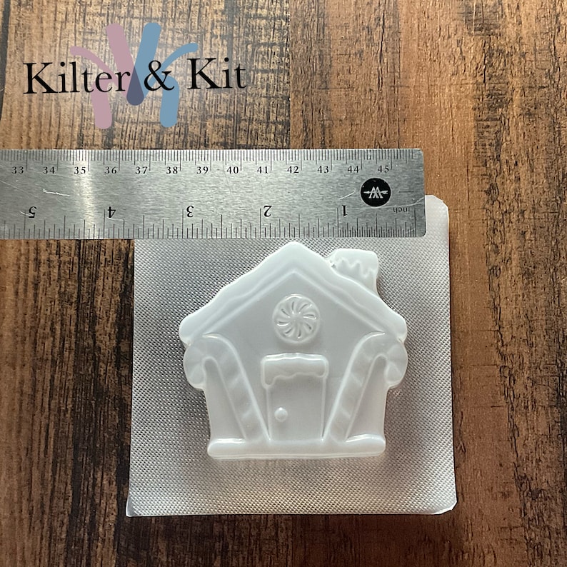 Puede incluir: Molde de pl&aacute;stico blanco de una casa de jengibre con detalles de bast&oacute;n de caramelo. El molde mide aproximadamente 5 cm de alto y 5 cm de ancho.