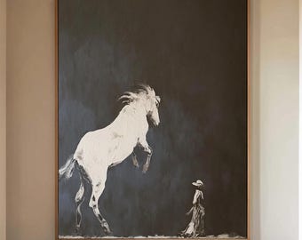以下が含まれることがあります： 暗い背景に白い馬が立ち上がっている大きな額入りのアートワーク。馬の下に人物が立っています。アートワークは、木のドアと模様のあるラグのある廊下に展示されています。