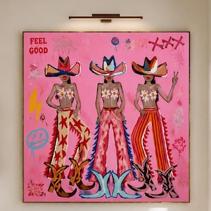May include: A large square painting on a pink background featuring three figures wearing cowboy hats and floral tops. The figures wear patterned pants and cowboy boots. The artwork includes graffiti-style elements, a yellow lightning bolt, and the text FEEL GOOD in the upper left corner.