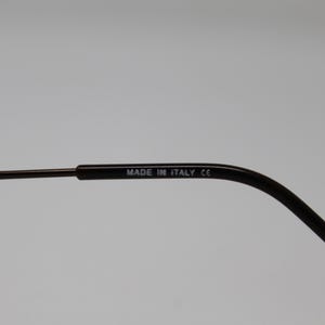 May include: Close-up of the arm of a pair of black eyeglasses with the text "MADE IN ITALY CE" printed on the arm.