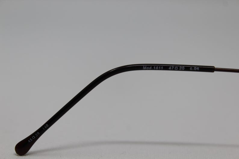 May include: Close-up of the arm of a pair of black eyeglasses. The arm is marked with the text "Mod. 1611 47□20 c.04 130 39 110".