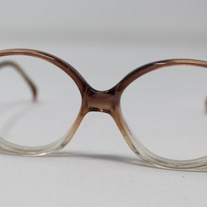 May include: Brown and clear plastic framed eyeglasses with a rounded shape.