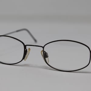 May include: A pair of black metal eyeglasses with oval-shaped lenses.