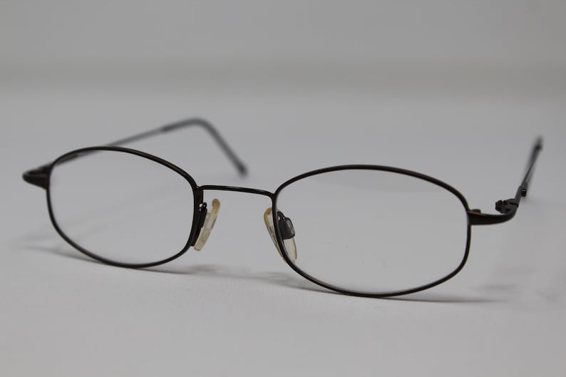 May include: A pair of black metal eyeglasses with oval-shaped lenses.