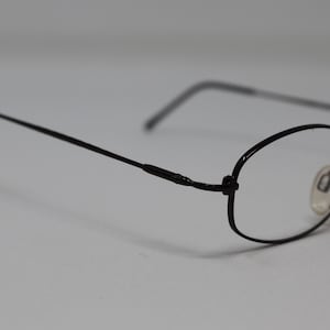 May include: Black metal framed eyeglasses with oval lenses.
