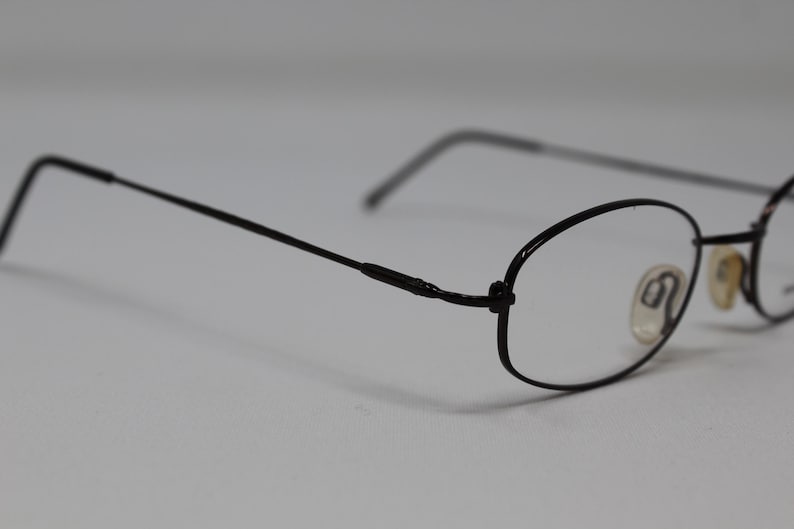 May include: Black metal framed eyeglasses with oval lenses.