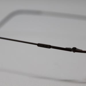 May include: A pair of brown metal eyeglasses with a thin frame and rectangular lenses.
