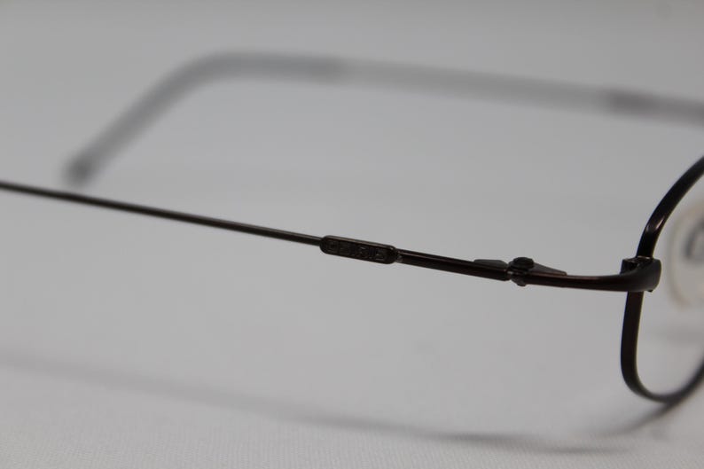 May include: A pair of brown metal eyeglasses with a thin frame and rectangular lenses.