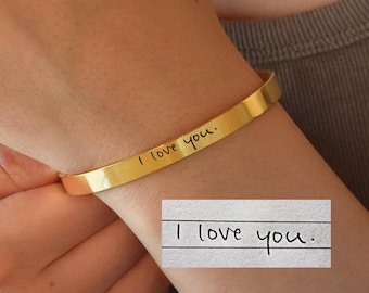 May include: Gold bangle bracelet with the inscription "I love you." The inscription is in handwritten font.