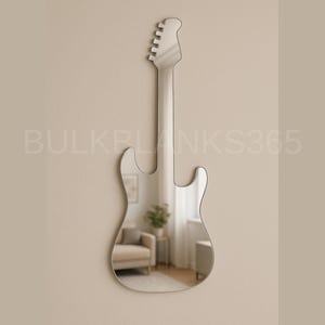 May include: A silver guitar-shaped mirror hanging on a beige wall. The mirror reflects a room with a beige armchair, a small table, and a plant. The text "BULKBLANKS365" is printed on the wall.