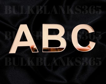 May include: Rose gold mirrored letters A, B, and C against a black background. The letters are reflective and appear to be made of acrylic or a similar material. The text "BULKBLANKS365" is faintly visible.