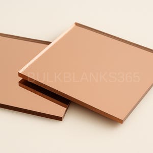 Puede incluir: Dos azulejos de espejo cuadrados y reflectantes de color cobre con bordes lisos y rectos. La superficie de los azulejos tiene un aspecto met&aacute;lico de oro rosa. El texto BULKBLANKS365 est&aacute; impreso en una fuente clara y semitransparente.