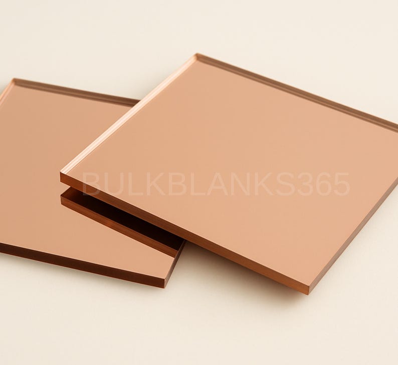 Puede incluir: Dos azulejos de espejo cuadrados y reflectantes de color cobre con bordes lisos y rectos. La superficie de los azulejos tiene un aspecto met&aacute;lico de oro rosa. El texto BULKBLANKS365 est&aacute; impreso en una fuente clara y semitransparente.