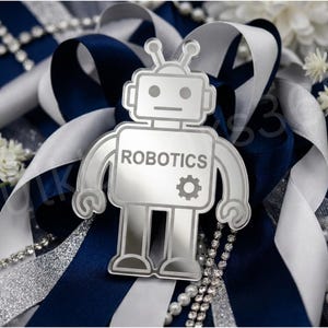 May include: A silver-toned, mirror-finish robot cutout featuring the word ROBOTICS and a small gear icon on its chest. The robot has a square head with two antennae, rectangular arms with claw hands, and rectangular legs with flat feet.