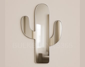 May include: A cactus-shaped mirror with a silver frame is mounted on a beige wall. The mirror reflects the room, and the design adds a touch of nature-inspired decor. The mirror's dimensions are approximately 24 inches tall and 15 inches wide.
