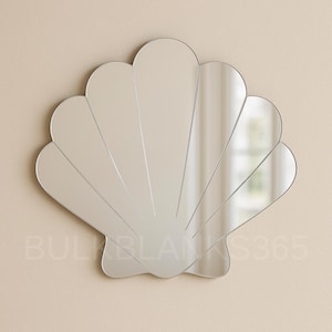 May include: A seashell-shaped mirror with a silver frame. The mirror is composed of multiple curved, petal-like sections, creating a fan-like design. The mirror is mounted on a light beige wall.