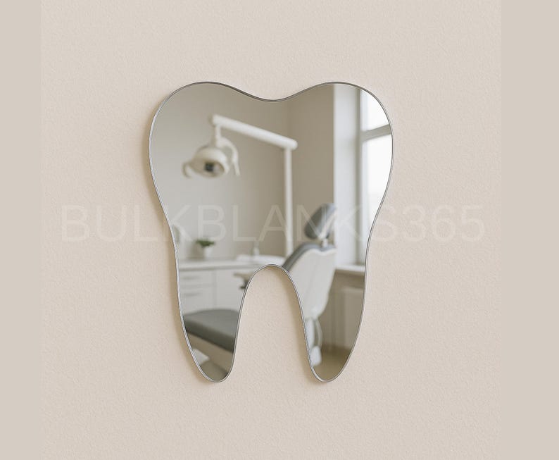 Op de afbeelding: Een tandvormige spiegel met een zilveren frame hangt aan een beige muur. De spiegel reflecteert een tandartspraktijk, inclusief een tandartsstoel, lamp en kasten. De vorm van de spiegel is een gestileerde weergave van een menselijke tand.