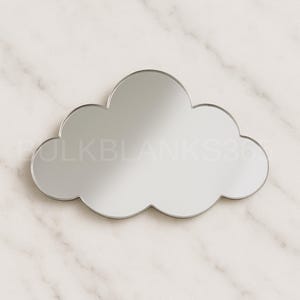 May include: A cloud-shaped mirror with a silver frame. The mirror has a reflective surface and is set against a marble background. The mirror's design is simple and modern, suitable for home decor.