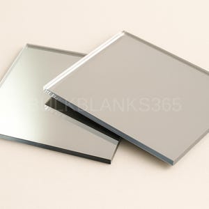 Puede incluir: Dos azulejos de espejo de vidrio cuadrados con superficies lisas y reflectantes y bordes rectos y limpios. El texto BULKBLANKS365 est&aacute; impreso en una fuente clara y semitransparente en el centro de las superficies de espejo superpuestas.