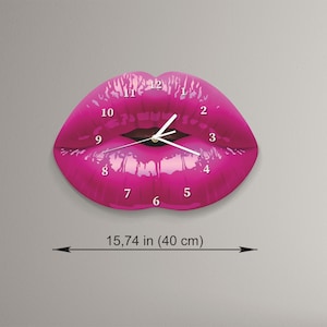 May include: A pink lips-shaped wall clock with white numbers and hands. The clock is 40 cm in diameter.