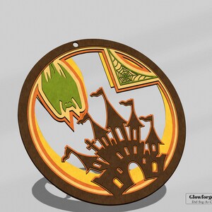 Könnte beinhalten: Ein runder Holzschmuck mit einem mehrschichtigen Design, das eine gruselige Burg, eine Fledermaus und ein Spinnennetz zeigt. Der Schmuck ist in Braun-, Orange-, Gelb- und Grüntönen bemalt.