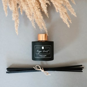 Può includere: Bottiglia diffusore nera con tappo dorato e bastoncini diffusori neri. La bottiglia ha un'etichetta bianca con il testo "Fuego Scent" e "HAND MADE IN LITHUANIA".