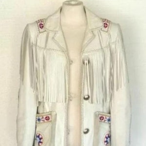 Könnte beinhalten: Eine weiße Lederjacke mit Fransenbesatz und bunten Stickereien. Die Jacke hat einen Knopfverschluss und zwei Taschen.