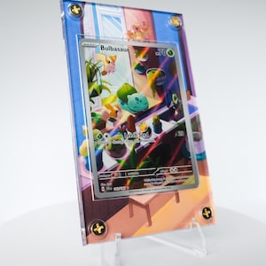 May include: A Bulbasaur Pokémon card encased in a clear acrylic holder, displayed on a clear stand. The card features a colorful illustration of Bulbasaur and other Pokémon. The holder is secured with gold-colored screws.