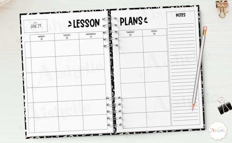 May include: Open lesson plan notebook with a black and white patterned cover. The notebook is open to a spread with the words "Lesson Plans" and a calendar layout. A pencil and binder clips are on the side.