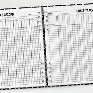 May include: Open notebook with a black and white patterned cover, featuring an attendance record and grade tracker. The left page has an apple graphic. A pencil and binder clips are on the right. The pages are lined for writing.