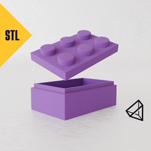 May include: A purple plastic storage box shaped like a Lego brick with the lid open. The box is about 15 cm long and 7.5 cm wide.