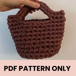 May include: A brown crocheted tote bag with a single handle. The bag is made with a thick yarn and has a simple, classic design. PDF PATTERN ONLY.