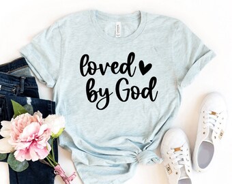 May include: A light blue t-shirt with the text "loved by God" in black lettering with a small black heart between the words.