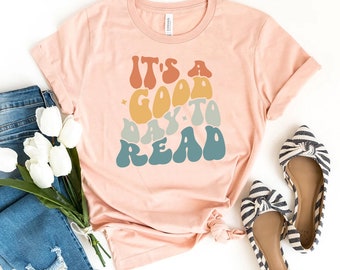 May include: A pink t-shirt with a retro-style graphic that says "It's a good day to read".