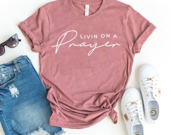 Peut inclure: Un t-shirt mauve avec le texte "Livin on a Prayer" en écriture blanche.