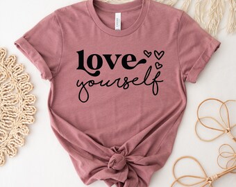 May include: A mauve t-shirt with the text "love yourself" in black lettering and small hearts.