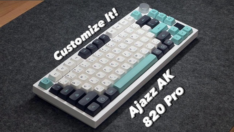 May include: A mechanical keyboard with a white frame, featuring a color scheme of white, dark gray, and light teal keycaps. The keyboard includes a silver rotary knob and displays the text "Customize It!" and "Ajazz AK 820 Pro" on the surface.