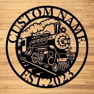 May include: Black metal silhouette of a steam train with smoke coming from the chimney. The train is on a track and the words "Custom Name Est. 2023" are around the train.