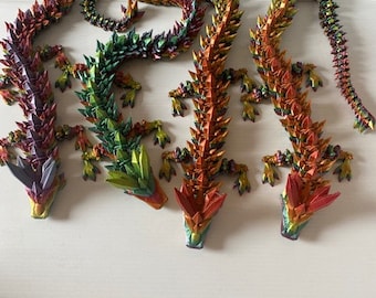 May include: Five origami dragons made of colorful paper. The dragons are arranged in a semi-circle, with their heads facing the viewer. The dragons are all different colors, including red, orange, yellow, green, and blue.