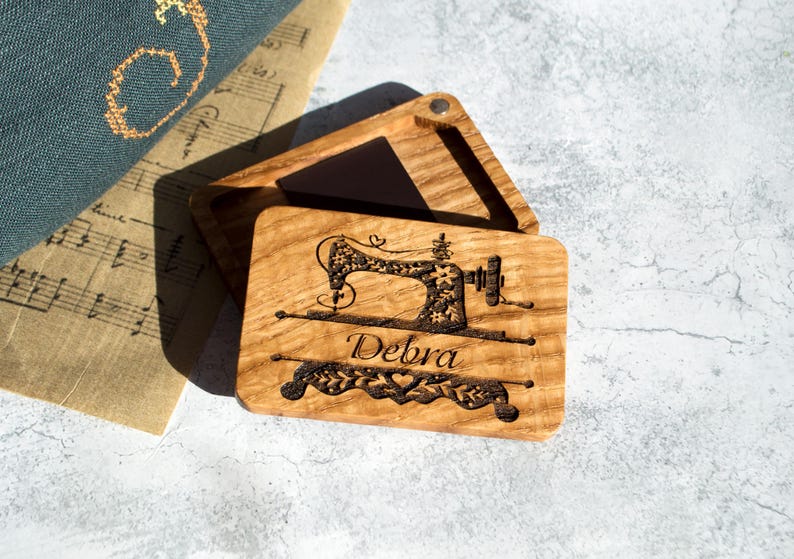 May include: A wooden box with a hinged lid, engraved with a sewing machine design and the name "Debra".
