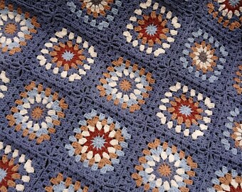 May include: A crocheted blanket with a blue background and a pattern of white, brown, and red circles.