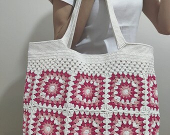 May include: A white crochet tote bag with pink and white granny squares. The bag has two long straps.