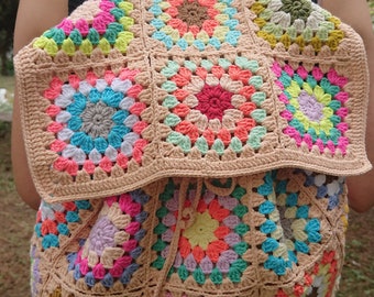 Può includere: Uno zaino all'uncinetto con un motivo a quadrati della nonna colorati. Lo zaino ha una chiusura a coulisse e spalline regolabili.