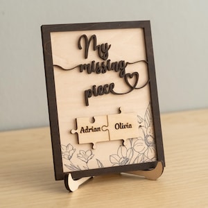 May include: Wooden sign with the text "My missing piece" and a heart symbol. Two puzzle pieces with the names "Adrian" and "Olivia" are attached to the sign.