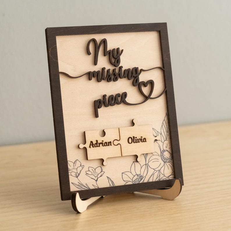 May include: Wooden sign with the text "My missing piece" and a heart symbol. Two puzzle pieces with the names "Adrian" and "Olivia" are attached to the sign.