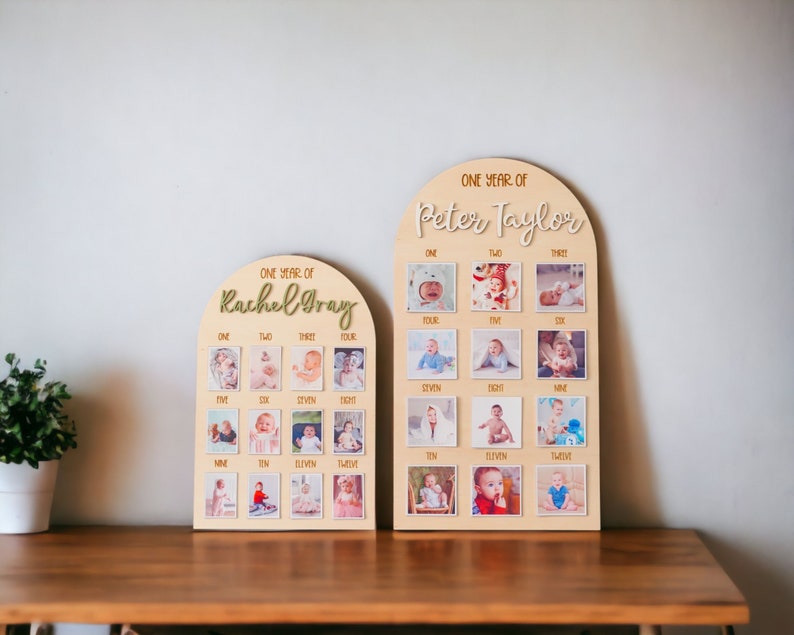May include: Two wooden photo display boards with arched tops. Each board has 12 square spaces for photos and the text "ONE YEAR OF" followed by a name. The name on the left board is "Rachel Gray" and the name on the right board is "Peter Taylor".