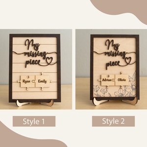 May include: Two wooden signs with the text "My missing piece" and a heart symbol. The signs have two puzzle pieces with names on them. The first sign has the names "Ryan" and "Emily" and the second sign has the names "Adrian" and "Olivia". The signs are on a wooden stand.