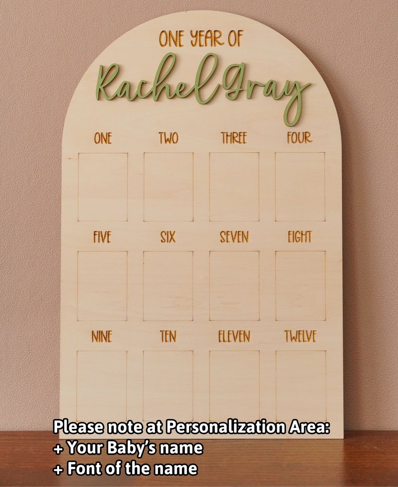 May include: A wooden arch-shaped board with the text "ONE YEAR OF Rachel Gray" at the top. The board has 12 empty squares labeled with the numbers one through twelve. The text "Please note at Personalization Area: + Your Baby's name + Font of the name" is at the bottom.