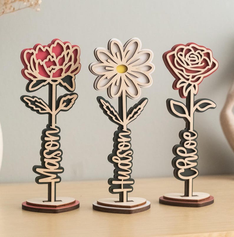 May include: Three wooden flower sculptures with red, white, and pink flowers. Each flower has a name written on the stem: "Mason", "Hudson", and "Grace".