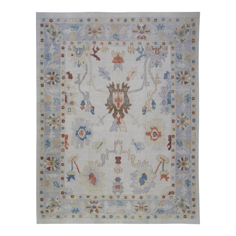 Pode incluir: Um tapete cinza claro com um padr&atilde;o floral em tons de azul, vermelho e marrom. O tapete tem uma borda com um padr&atilde;o repetitivo de pequenos c&iacute;rculos e flores.